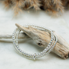 Silver bracelets on a piece of driftwood with a natural background