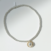 Silver bracelet with a gold charm on a white plate