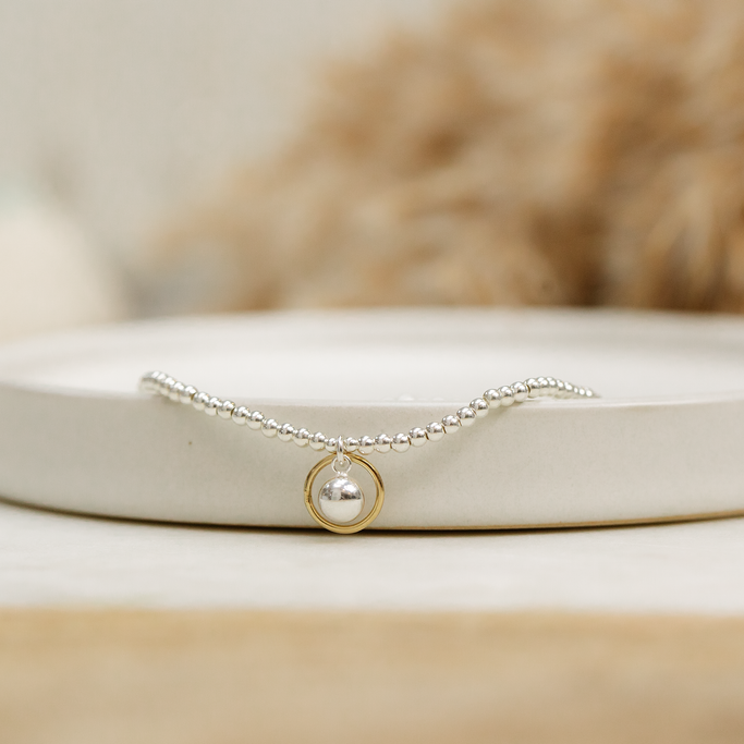 Silver necklace with a gold pendant on a white surface