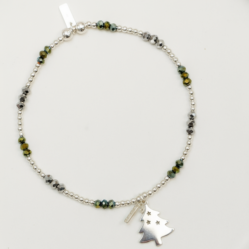 Bracelet with green beads and a tree charm on a white plate